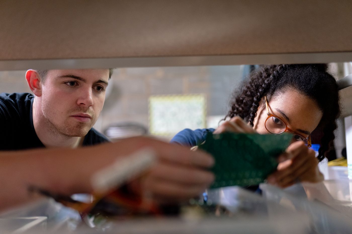 Engineers examining an electronic circuit board in a workshop